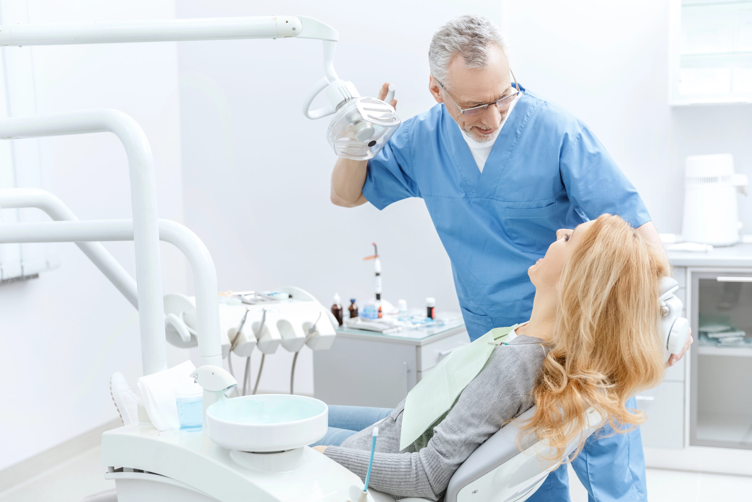 A dentist interacts with a patient in a modern dental clinic, preparing for an emergency wisdom tooth extraction to address sudden pain or complications.