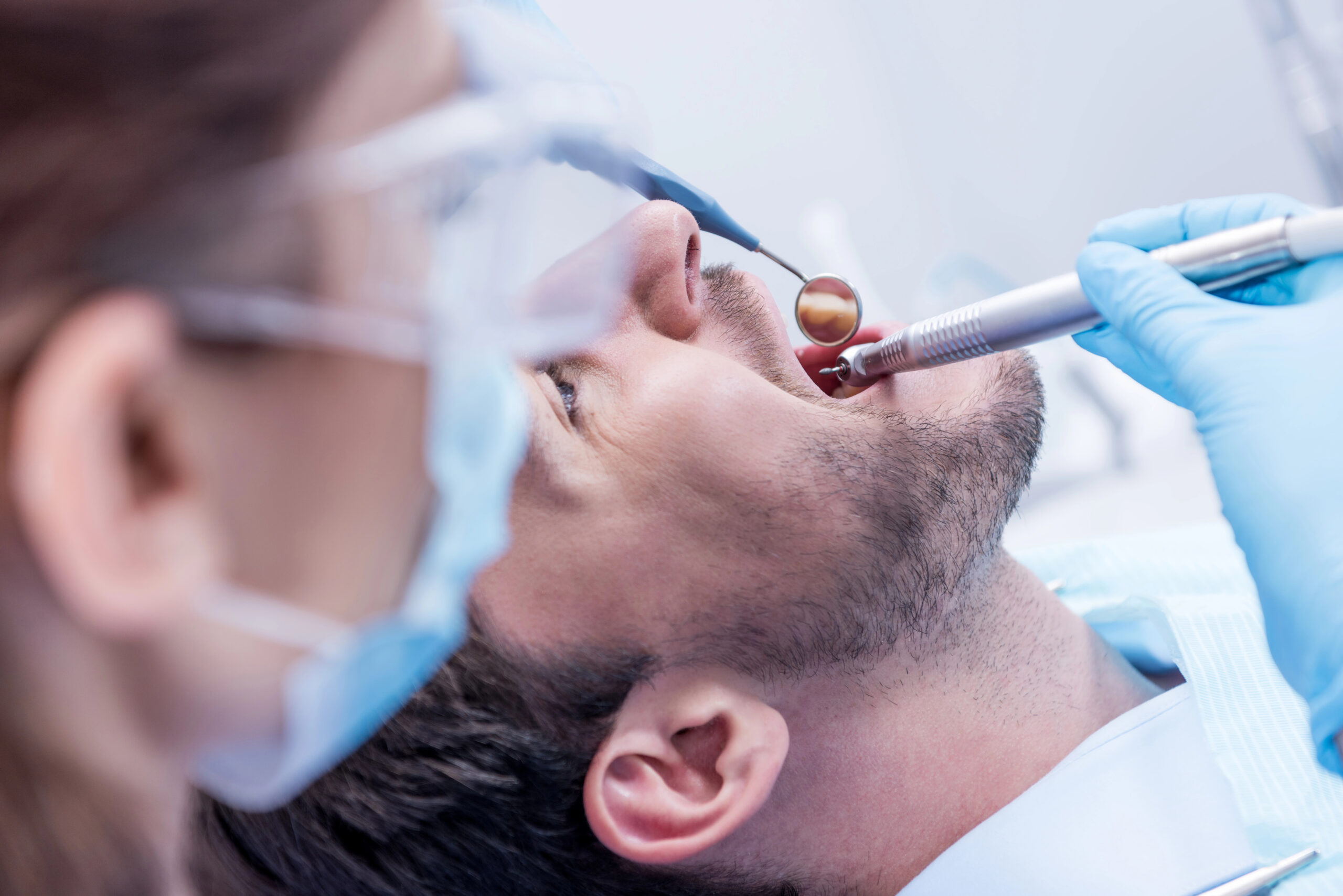 A dentist carefully examines and treats a patient using specialized tools, focusing on preventing or addressing a wisdom teeth removal infection for proper healing.