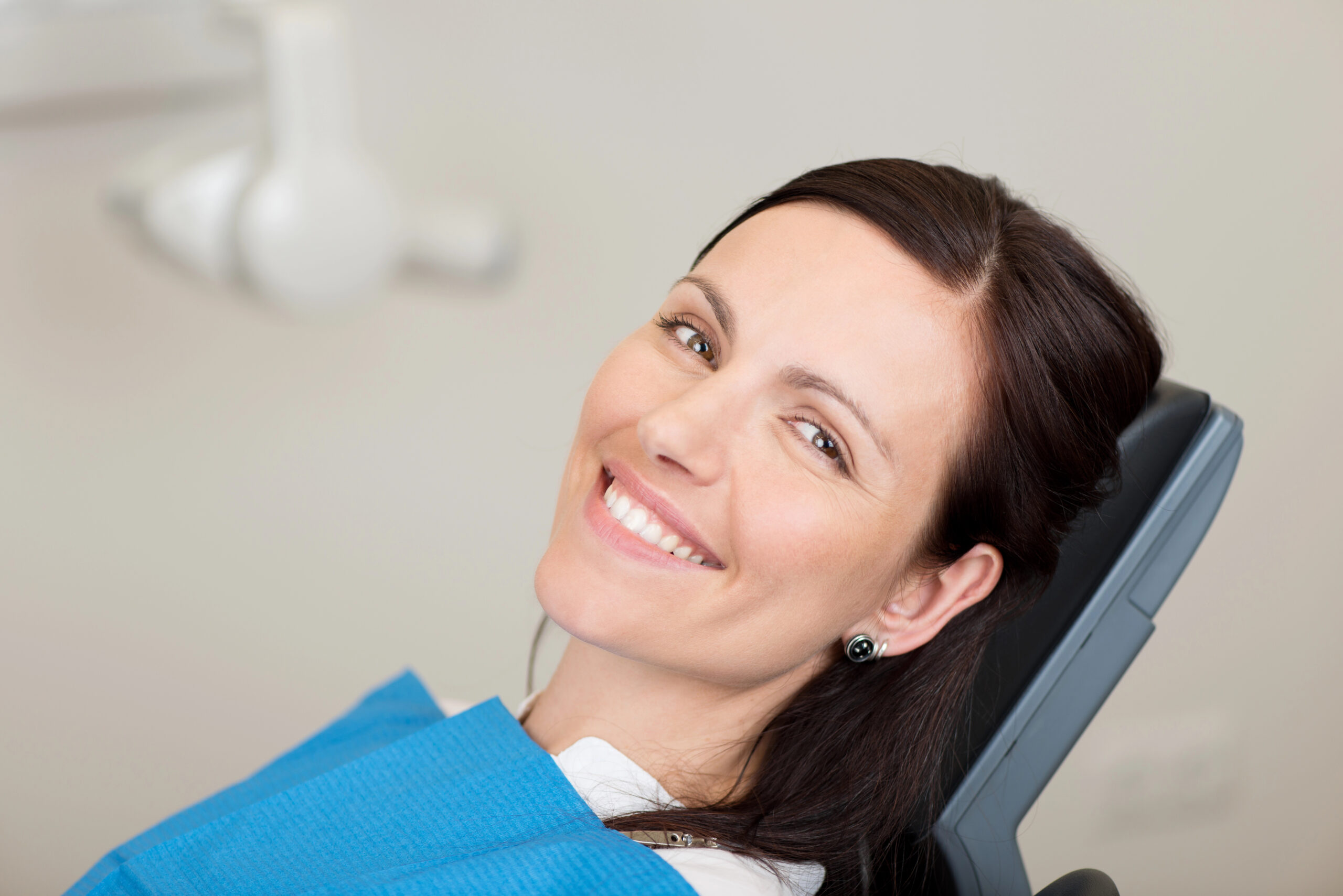 A smiling patient relaxes in a dental chair, reflecting confidence and comfort, possibly after receiving guidance on post wisdom teeth removal care for optimal recovery.