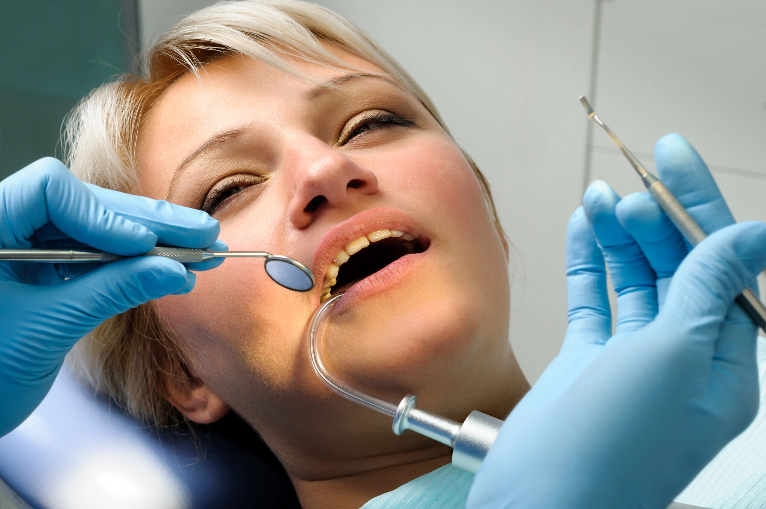 A patient is undergoing a dental procedure with professional tools and assistance, often associated with treatments like addressing swelling after wisdom teeth removal.